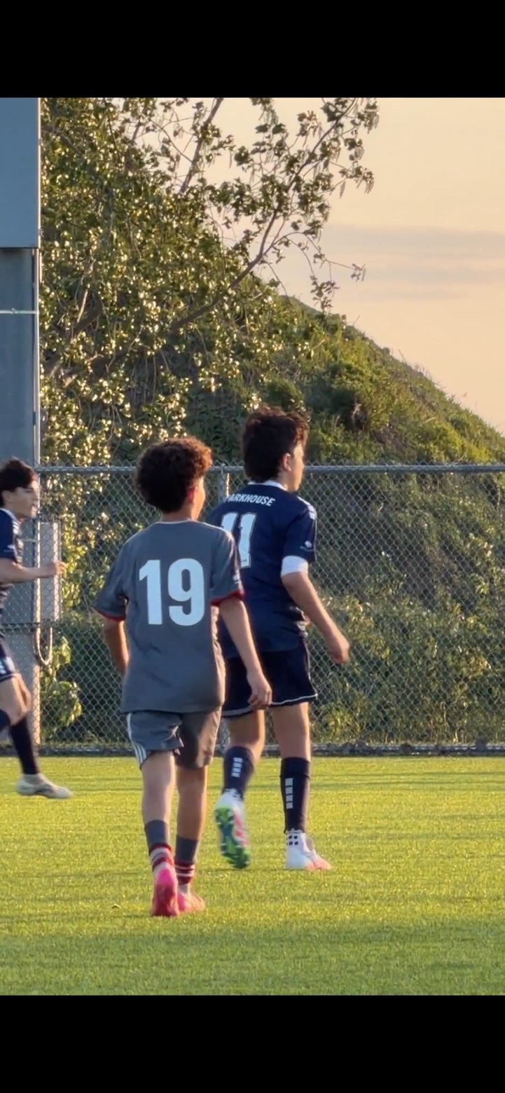 Zain Al Haj Ali walking the pitch at golden hour alongside a teammate.